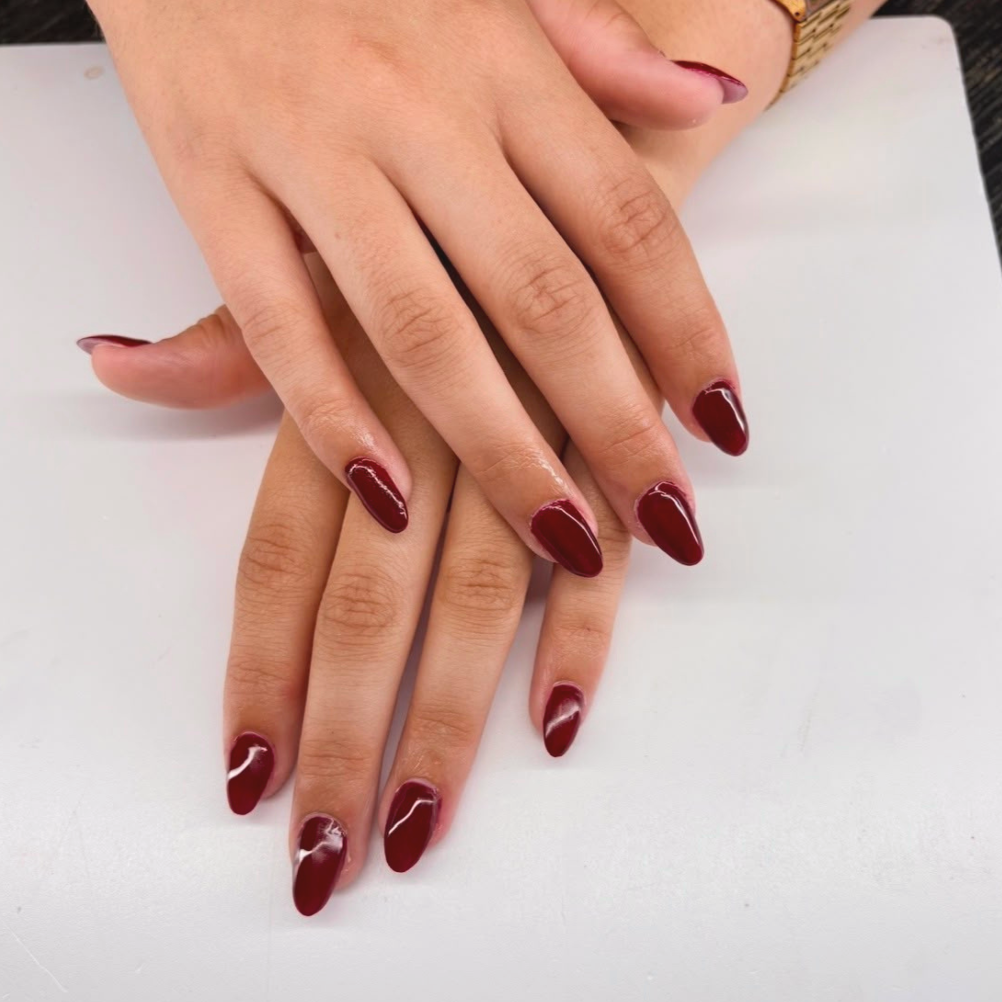 Verzorgde amandelvormige nagels in een diepe bordeauxrode gellak